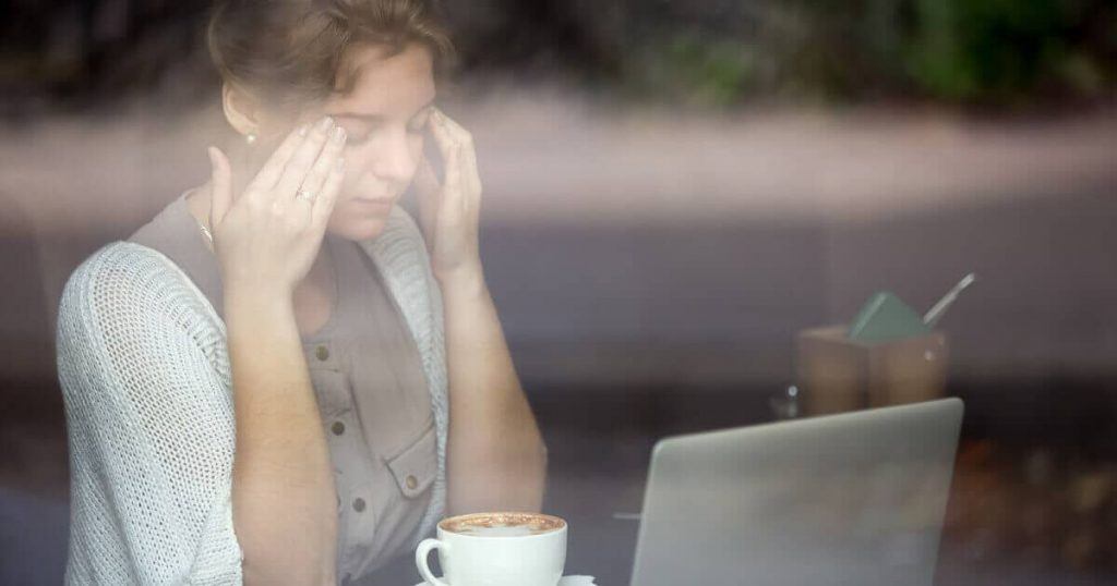 Frau gestresst im Job vor Laptop